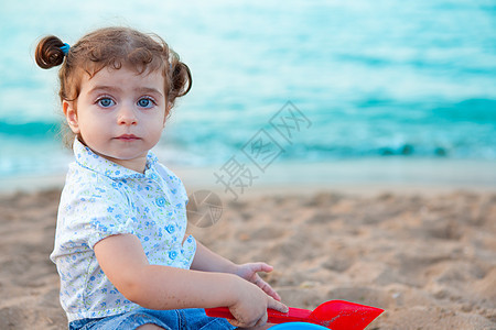 在沙滩上玩沙子的蓝褐色眼睛辫子假期海洋女性海滩喜悦幸福旅行游戏支撑图片