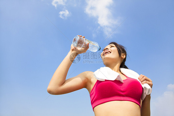 年轻女性在健身锻炼后饮用饮用水蓝色活动活力晴天慢跑者运动员毛巾成人赛跑者瓶子图片