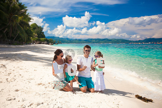 四口的年轻美丽家庭 享受沙滩上放松的快乐喜悦父母女孩父亲海岸婴儿假期母亲女儿海岸线图片