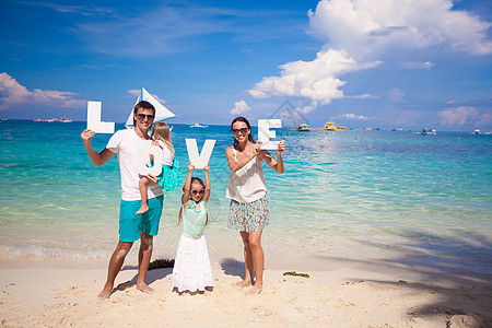 四口幸福的年轻家庭 在热带度假 带字词爱海岸爸爸异国女士女儿女孩享受海岸线情调母亲图片