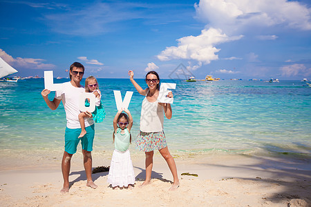 年轻家庭和两个孩子在热带度假时 有爱字词父亲父母爸爸女孩女性乐趣假期母亲海洋女儿图片