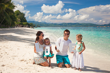 年轻家庭和两个孩子在热带度假时 有爱字词母亲父亲女儿喜悦旅游男性享受女孩成人海洋图片