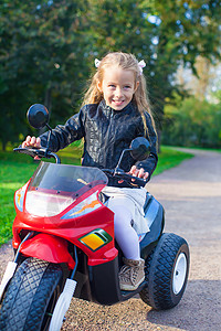 穿着皮夹克的可爱快乐的小姑娘 坐在玩具摩托车上姐姐运输情感幼儿园乐趣速度喜悦童年自行车女孩图片