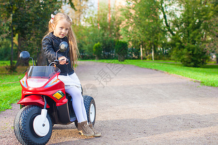 车家人可爱的小女孩在玩具摩托车上玩得开心游戏婴儿微笑运动晴天孩子娱乐幼儿园喜悦运输背景