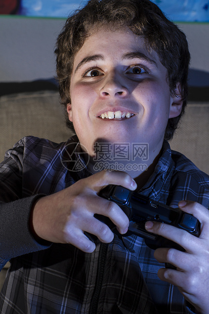 在家玩电脑游戏的玩棍子的嬉皮男孩青少年手柄闲暇电脑喜悦男生童年沙发技术男性图片