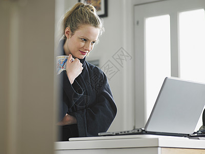 使用膝上型电脑站在厨房低角度视图下方的妇女图片