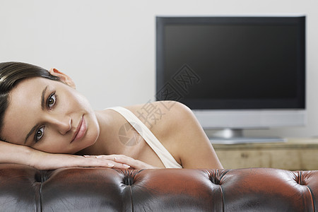 沙发上年轻女性在平板屏幕电视肖像前微笑摄影娱乐真皮女士成人黑发一人活动客厅图片