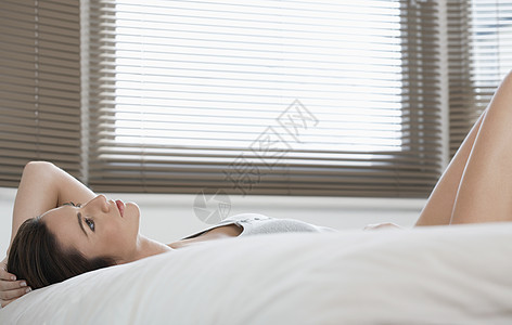 躺在床上寻找的年轻女人沉思男人卧室羽绒被黑发成年女士床罩女性床单图片