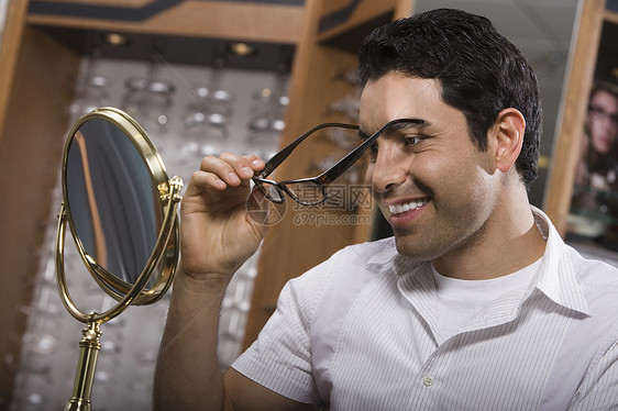 男人在商店里试戴眼镜快乐男子店铺眼镜头肩顾客保健中年黑发镜子图片