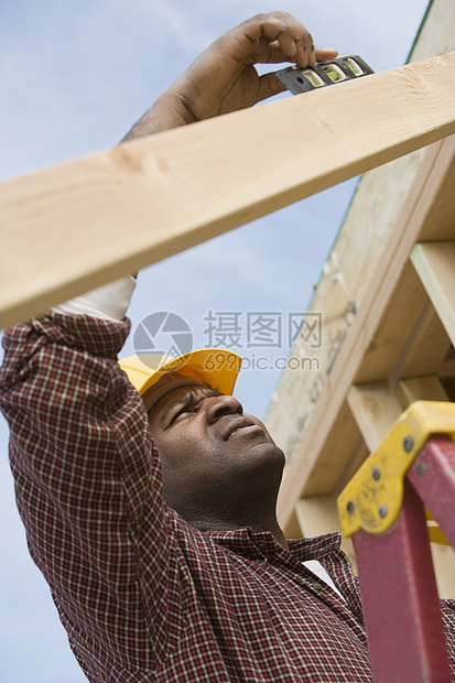 建筑工人在建筑物上运用精神水平的建筑工人裁剪安全帽职业技术层面低角度安全视图结构头肩图片