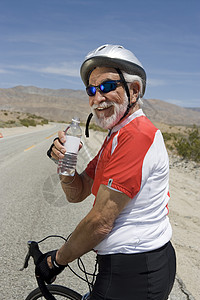 拥有自行车饮用水的老年男子闲暇服装瓶子沙漠生活方式微笑活动运动水壶男士图片