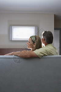 坐在沙发上看着电视后视的一对夫妇图片