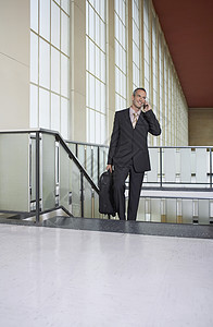 商务人士在楼梯上机场大厅前厅使用手机的人图片