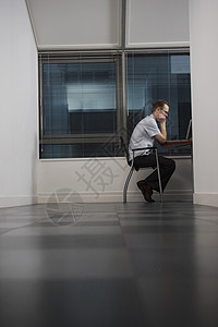 在部分黑暗的办公室侧视图中使用计算机的办公工作人员高清图片