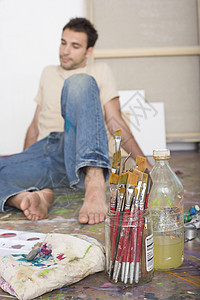 男艺术家坐在一个工作室的地板上 用绘画工具坐在地上图片