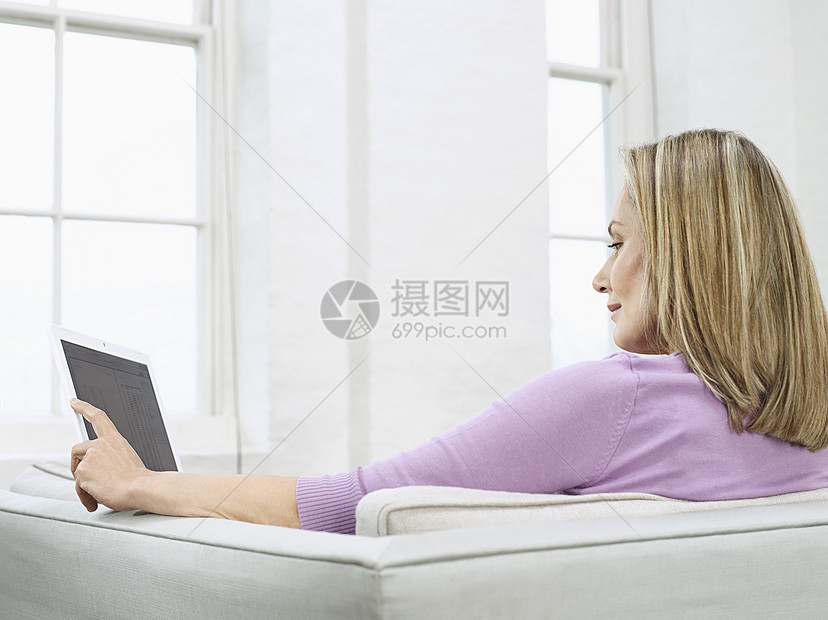 在沙发剖面图上使用笔记本电脑的中成年妇女图片