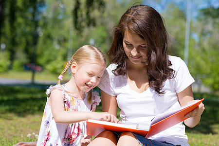 女孩和年轻女子一起阅读一本书学生拥抱微笑女性家庭闲暇学习老师教育婴儿图片