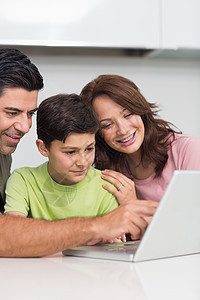 使用笔记本电脑与儿子一起微笑的一对夫妇母亲父亲童年公寓男人父母互联网学习闲暇女士图片