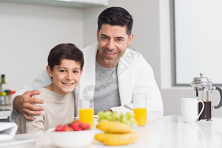 年少儿子和父亲在厨房吃早餐图片