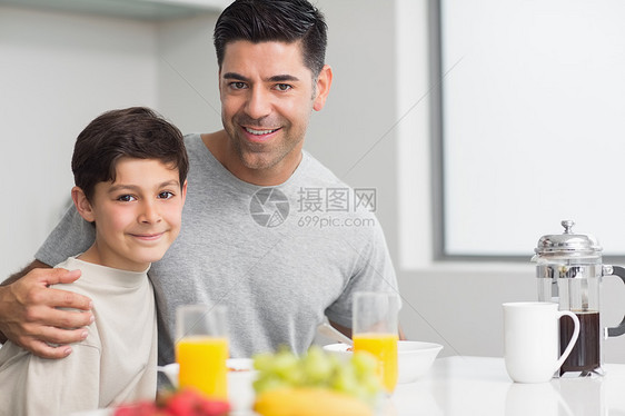 和父亲一起吃早餐的快乐儿子的肖像幸福餐桌孩子橙汁成人微笑房子水果玻璃公寓图片