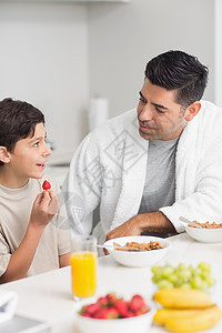 微笑的年轻儿子和父亲一起吃早餐图片