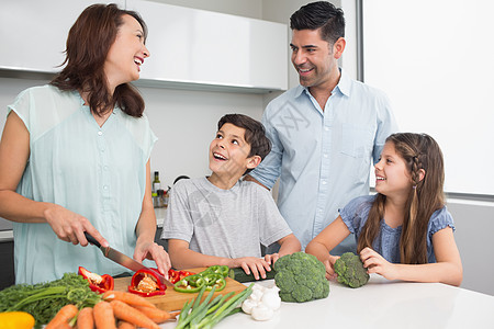 家庭在厨房里切菜蔬菜童年父亲女性女士切菜板学习母亲儿子幸福微笑图片