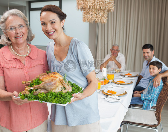 妇女和祖母在餐桌上与家人一起吃烤鸡肉的女士和祖母母亲食物快乐男生用餐孩子祖父母家庭生活父亲晚餐图片