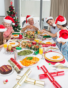 享受圣诞晚宴的圣诞老人帽子家庭快乐图片