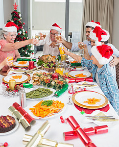 家庭在圣塔的帽子 烤红酒杯 在餐桌上父母用餐午餐橙汁小玩意儿男人团结母亲家庭生活男性图片