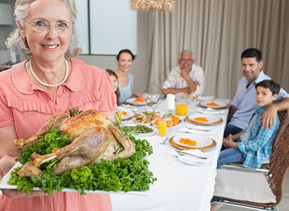 祖母在饭桌上与家人一起吃烤鸡肉的女孩祖父母餐桌兄弟父母女性桌子男人晚餐老年图片