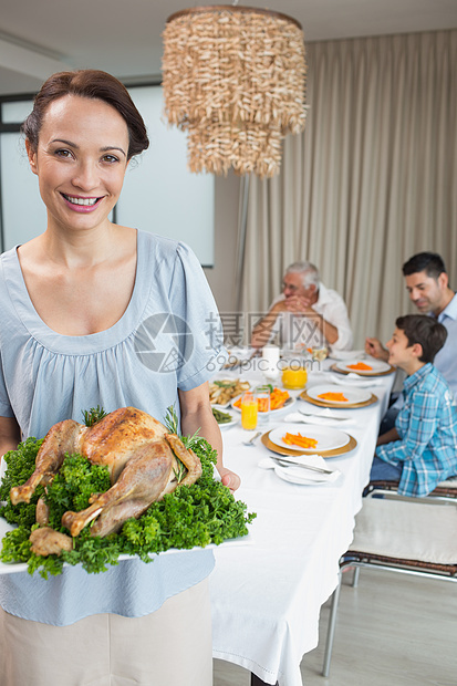 与家人一起在餐桌上吃烤鸡肉的妇女父母家庭生活吊灯午餐男人盘子房子家庭成人父亲图片