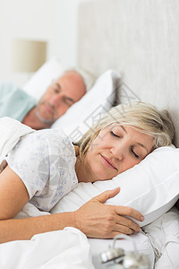 在床上闭着双眼睡觉的成熟夫妇家庭生活女性房子夫妻床单休息眼睛枕头卧室男性图片