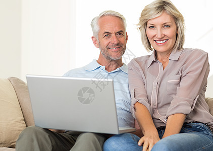 在沙发上使用笔记本电脑的幸福成熟夫妇长椅男人男性家庭生活微笑技术房子夫妻女性客厅图片