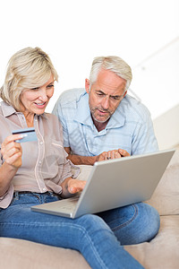 在家网上购物的成熟夫妇人数百分比信用卡沙发电子男性夫妻房子女性专注互联网电脑图片