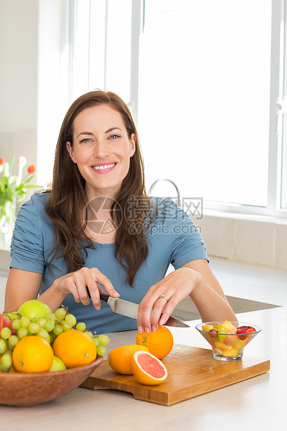 一个女人在厨房里割水果的肖像女性切菜板头发闲暇房子棕色女士柜台图片
