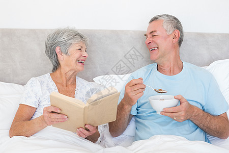 幸福的一对夫妇与书和碗在床上图片