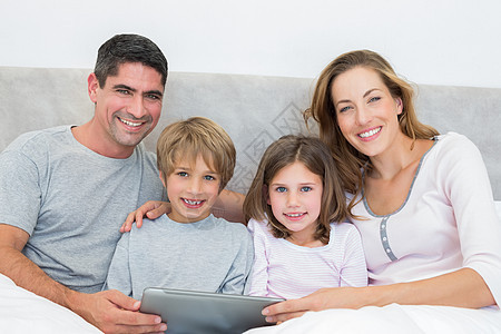床上有数字平板电脑的家庭女性女儿卧室男生男人母亲睡衣兄弟房子姐姐图片