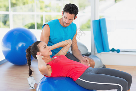 男性教练员帮助妇女在体操中锻炼健身房运动员教学火车瘦身拉伸平衡女性健身室培训师图片