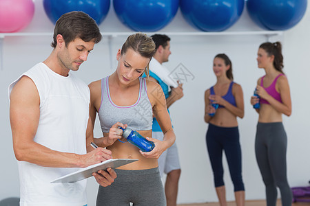 夫妇一起看剪贴板 背景上健康课班级俱乐部培训师运动服女士朋友们健身室运动员调子工作室图片