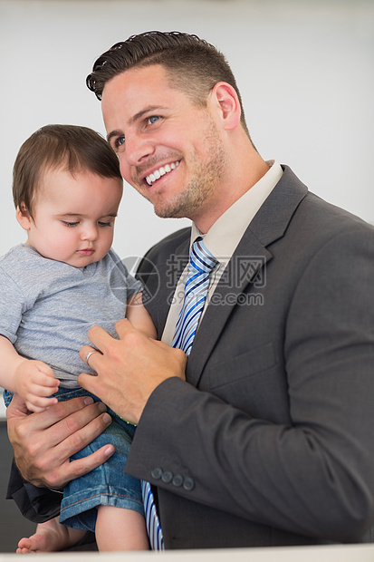 在家带婴儿男孩的商务人士图片