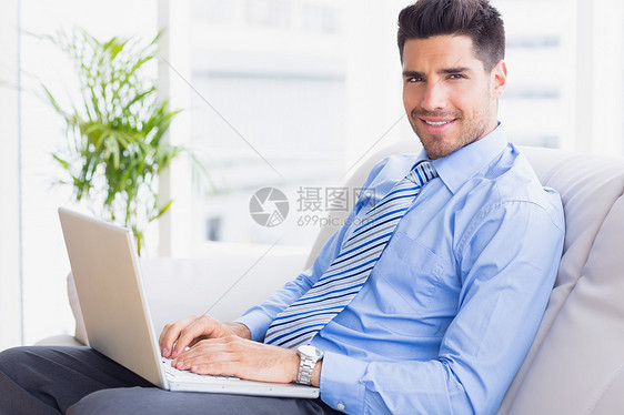 商务人士坐在沙发上 用笔记本电脑微笑着照相机图片