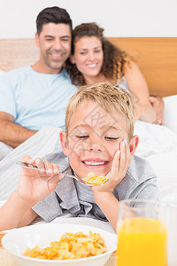 可爱的年轻家庭在床上吃早餐图片