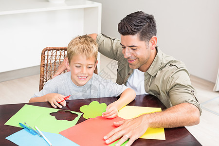 父亲和儿子在桌边一起做纸的形状图片