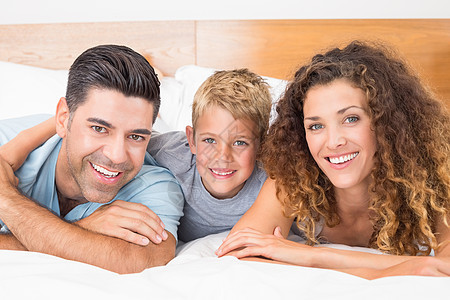 躺在床上微笑的年轻家庭看着照相机图片