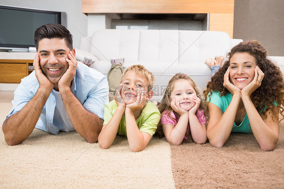 幸福的兄弟姐妹们躺在地毯上 与父母一起摆布图片