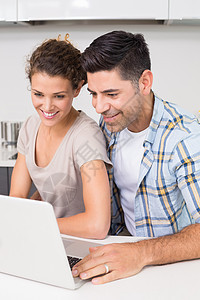 使用笔记本电脑一起微笑的情侣快乐女士男性家庭闲暇成人房子夫妻台面柜台图片