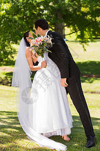 罗马新婚夫妇在公园接吻团结联盟妻子婚姻花束套装婚纱女性树木草地图片