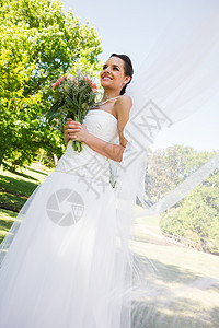 快乐的年轻美丽的新娘 带花束在公园图片