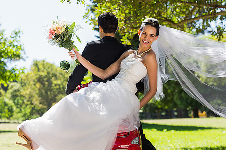 新婚夫妇坐在公园的摩托车上丈夫微笑婚礼旅行女士联盟妻子草地新人女性图片