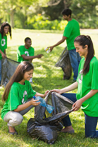 志愿者小组在公园里捡起垃圾朋友们整理塑料瓶社区志愿机构道德混血服务打扫图片